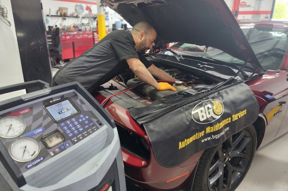Car AC repair services in Chandler, AZ at Mac’s Complete Auto Repair. Image of mechanic using Robinair AC12345-6 equipment to recharge auto air conditioning in a Red Dodge Challenger.