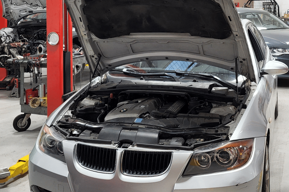 BMW Maintenance and Repair in Chandler, AZ by Mac’s Complete Auto Repair. Image of a BMW with the hood open in a professional auto repair shop, showcasing the inspection and maintenance process to address potential cooling system issues.