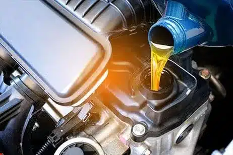 Image of fresh engine oil being poured into a car engine after an oil change.