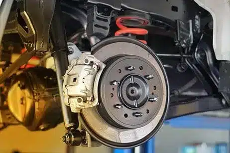 Brake repair in Chandler,AZ at Mac's Complete Auto Repair. Closeup image of new brake pads and rotors on white car in shop.