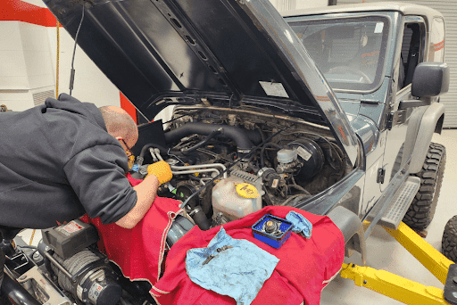 Trustworthy auto repair shop for Jeeps, Lexus, Subaru, Toyota, Toyota Prius, Ford and Volkswagens in Chandler, AZ. Image of Mac’s mechanic performing auto repairs on a gray Jeep wrangler in the shop with tools.