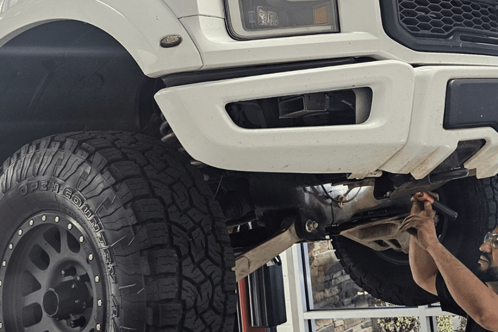 Fleet maintenance in Chandler, AZ by Mac’s Complete Auto Repair. Image of a mechanic working underneath a lifted truck with off-road tires, highlighting the shop’s dedication to safety, stability, and peak vehicle performance.