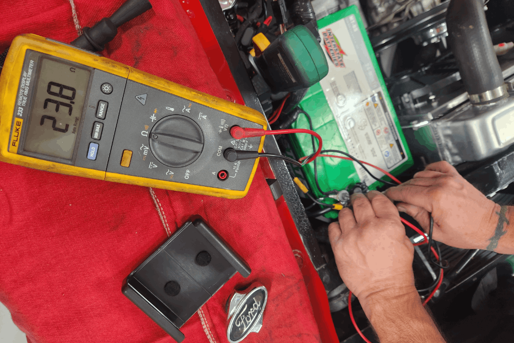 Battery maintenance in Chandler, AZ by Mac’s Complete Auto Repair. Image of a technician using a multimeter to check voltage and connections on a vehicle battery during service.