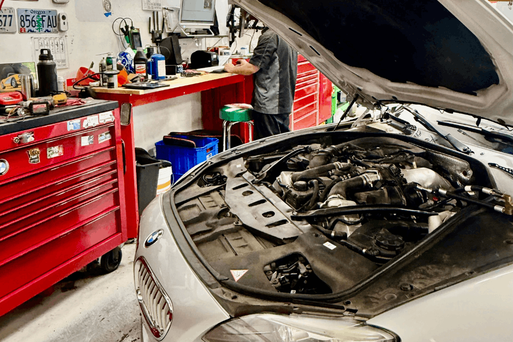 National Car Care Month, auto repair in Chandler, AZ by Mac's Complete Auto Repair. Image of BMW engine bay with technician workspace, highlighting thorough inspections, preventative maintenance, and reliable performance for European vehicles.